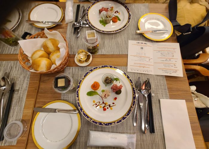 A table laid with plates, cutlery, bread rolls, and small dishes at Lakeside Grill.